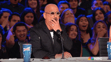 a man covering his mouth while sitting at a table with a sonic cup