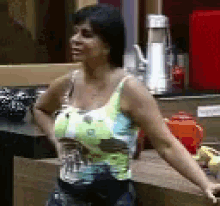a woman in a tank top is standing in a kitchen .