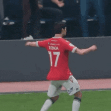 a soccer player wearing a red jersey with the number 17 on it is dancing on a field .