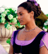 a woman is wearing a purple dress and a purple necklace with a flower in her hair