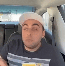 a man wearing a hat and a striped shirt is sitting in a car .