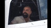 a man with a beard is sitting in the driver 's seat of a white truck