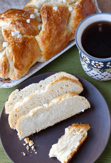 a slice of bread sits on a plate next to a bowl of coffee