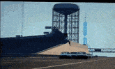 a group of cars are driving down a highway in front of a water tower