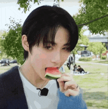a young man is eating a slice of watermelon .