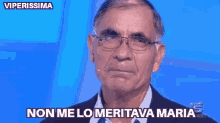 a man wearing glasses and a suit says " non me lo meritava maria "