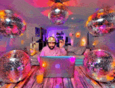a man wearing headphones is using a laptop in a room with disco balls hanging from the ceiling