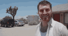 a man wearing sunglasses and a white shirt is smiling in front of a motel