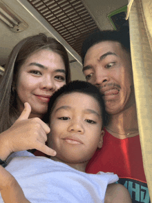 a man wearing a red shirt with the letter h on it poses with his wife and child