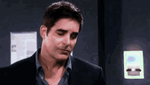 a man in a suit and blue shirt is standing in a dark room looking down