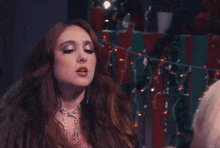 a woman with long red hair is covering her mouth with a black glove