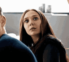 a woman is sitting next to a man on a couch and looking at the camera .