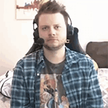 a man wearing a plaid shirt and headphones is sitting in a chair .