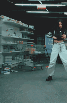a woman in a black top and white pants is dancing in front of a sign that says persil