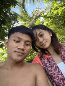 a man and a woman are posing for a picture in front of palm trees