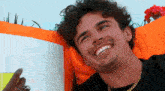 a man with curly hair is smiling while laying on an orange chair