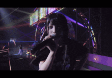 a woman singing into a microphone in front of a colorful stage
