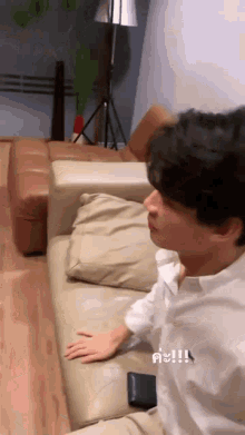 a man is sitting on a couch with his hand on the cushion .