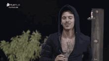 a man in a black hoodie is smiling and holding a cup