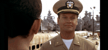 a man in a military uniform stands in front of a ship