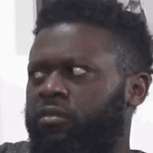 a man with a beard is making a funny face while looking at the camera .