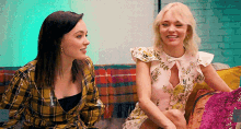 two women are sitting on a couch and talking to each other .