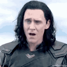 a close up of a man with long black hair making a surprised face .