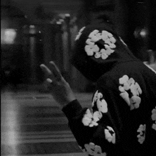 a person wearing a black hoodie with white flowers on the sleeves