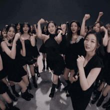 a group of young women in black dresses are dancing