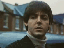a close up of a man 's face wearing a turtleneck sweater and a suit .