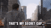 a man is walking down a city street with the words that 's my secret cap