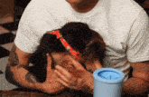 a man holds a puppy in his arms next to a blue container