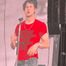 a man in a red shirt is singing into a microphone