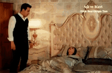 a man is standing next to a woman laying on a bed