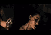 a close up of a woman 's face in a dark room with her eyes closed