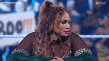a woman is sitting in a wrestling ring with her hands on her knees .
