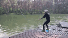 a man is riding a wakeboard on a dock in front of a lake with the words sailarmy written on the bottom