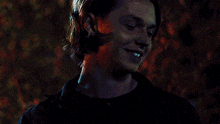 a close up of a man 's face in a dark room with a tree in the background .