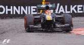 a race car is driving on a track with an advertisement for ohnnie walker behind it