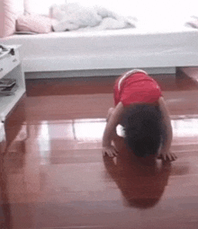 a child is doing a handstand on a wooden floor