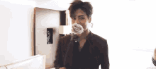 a man in a suit is holding a rose in his mouth in a hotel room .
