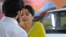 a man and a woman are kissing in front of a white car .