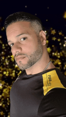 a man with a beard wears a black shirt with a yellow patch that says pwr-112