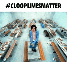 a man in a blue jacket is dancing in a room with tables and benches and the words #clooplivesmatter above him