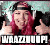 a woman with pink hair is giving a thumbs up while wearing headphones and a hat .