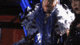 a woman with blue hair and white feathers on her shoulder