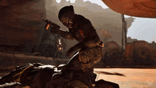 a video game character is kneeling down and holding a gun while another character is laying on the ground