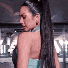 a woman with a ponytail and hoop earrings looks over her shoulder