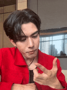 a young man wearing a red jacket is making a funny face