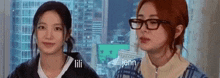 two girls wearing glasses are standing next to each other and looking at the camera .